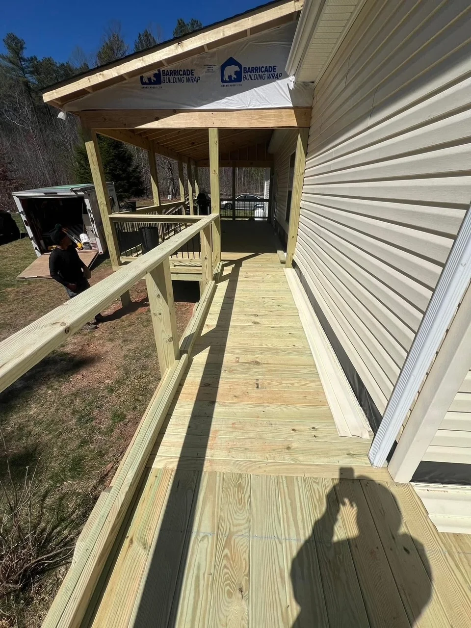 Pressure-treated wood deck with metal railings and covered roof structure under construction