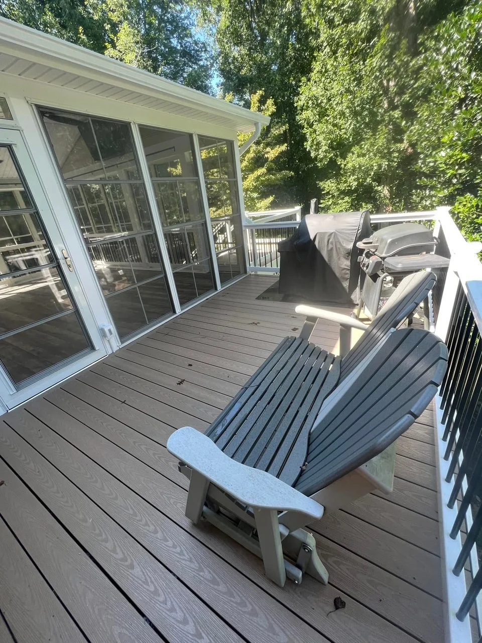 Composite deck with Adirondack chairs and screened porch with glass doors and aluminum railings