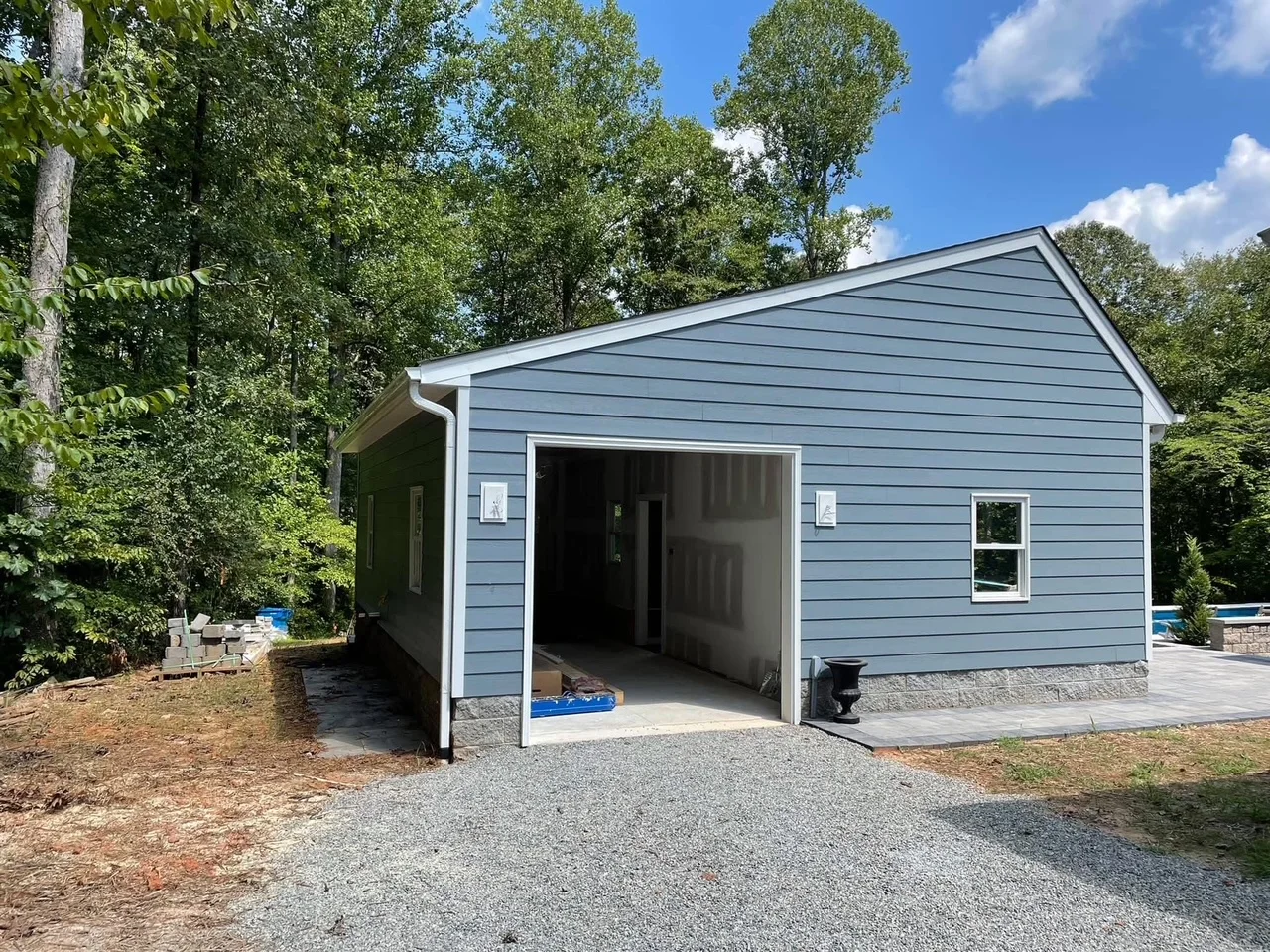 New garage with blue siding, white trim, gable roof, and open garage door