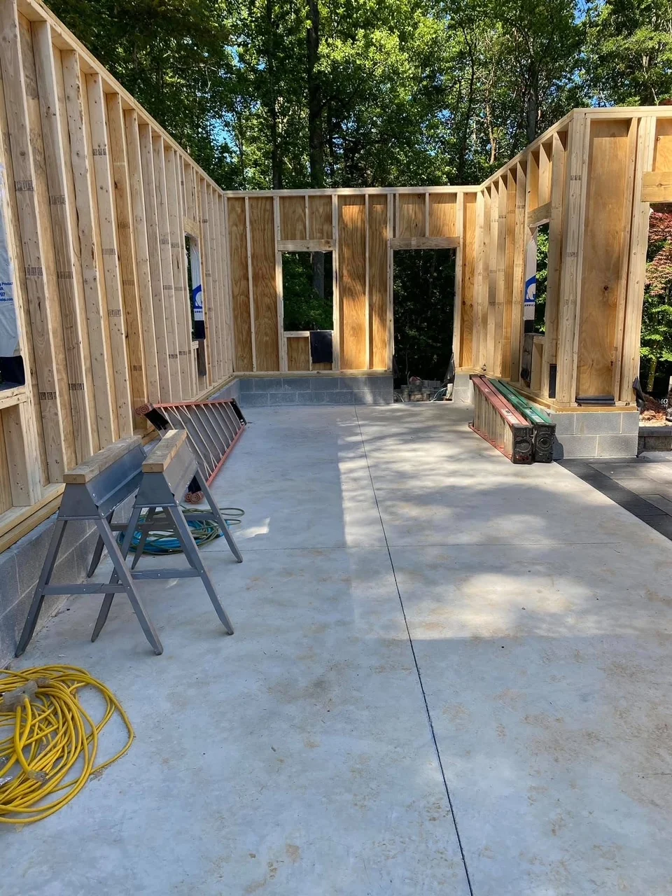 Wood-framed structure with concrete slab, vertical studs, window openings, and control joints