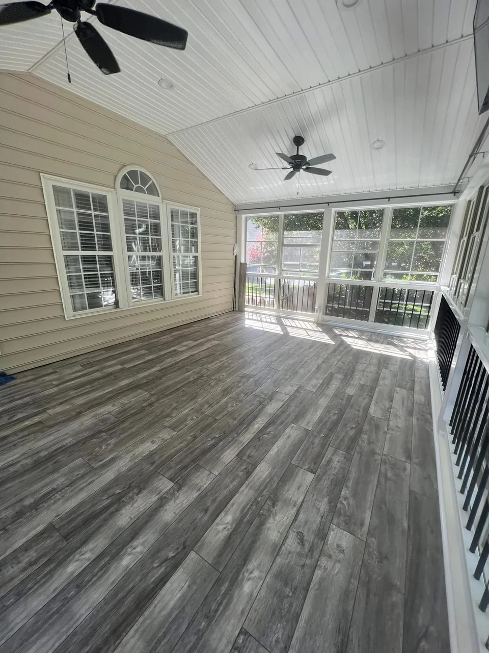 Screened porch with gray vinyl plank flooring, white beadboard ceiling, and large window panels