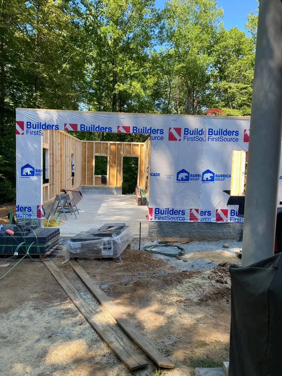 Wood framed house structure with weather wrap, door and window openings, concrete foundation