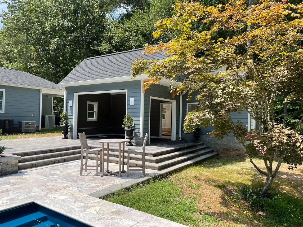 Gray siding home addition with covered porch, composite patio, and tiered paver steps